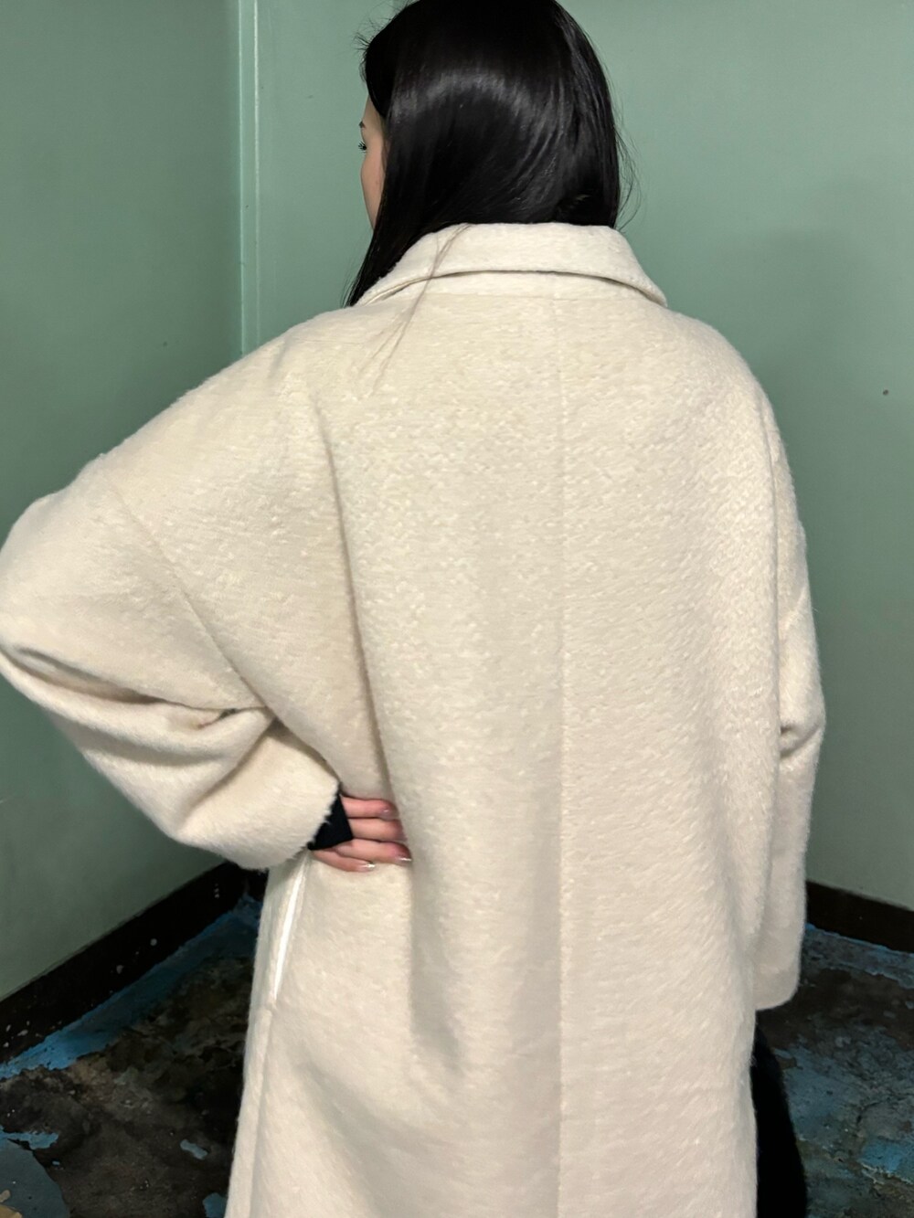 ホワイト系のチェスターコート、ブラック系のブーツ、ブラック系のハンドバッグを着用したレディースの冬コーディネートの6枚目の写真