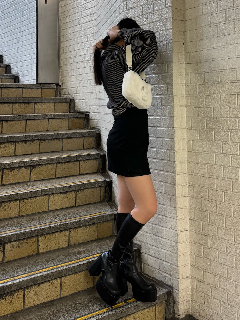 ブラック系のニット/セーター、ブラック系のスカート、その他のブーツを着用したレディースの秋コーディネートの2枚目の写真