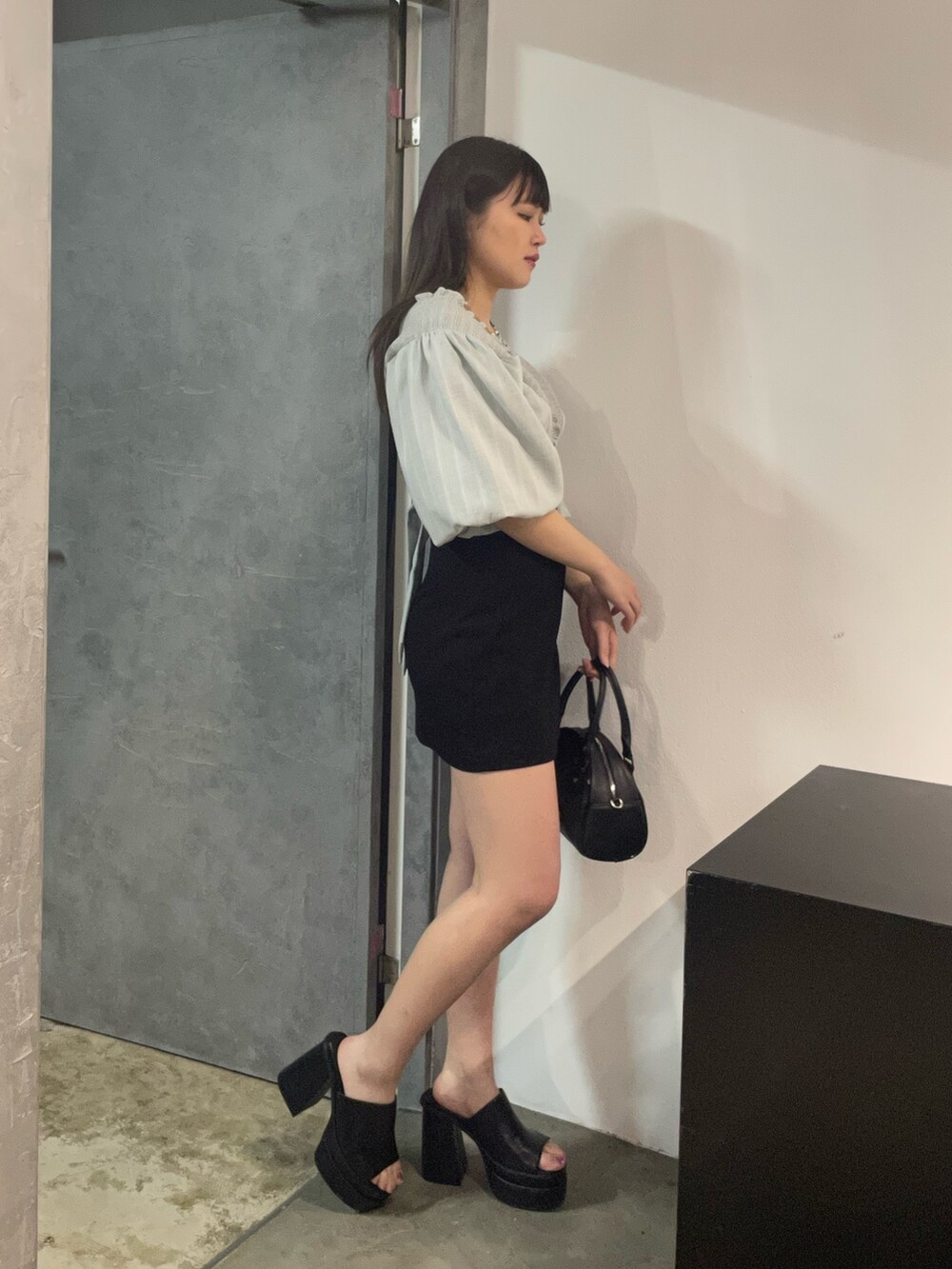 その他のハンドバッグ、ブラック系のスカート、ブラック系のサンダルを着用したレディースの春コーディネートの2枚目の写真