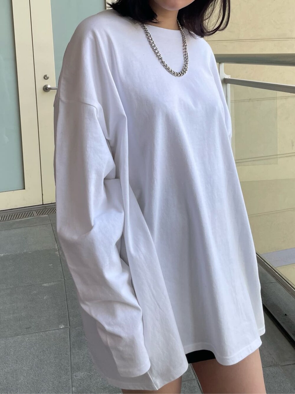 ホワイト系のブーツ、ホワイト系のTシャツ/カットソー、ブラック系のスカートを着用したレディースの春コーディネートの6枚目の写真