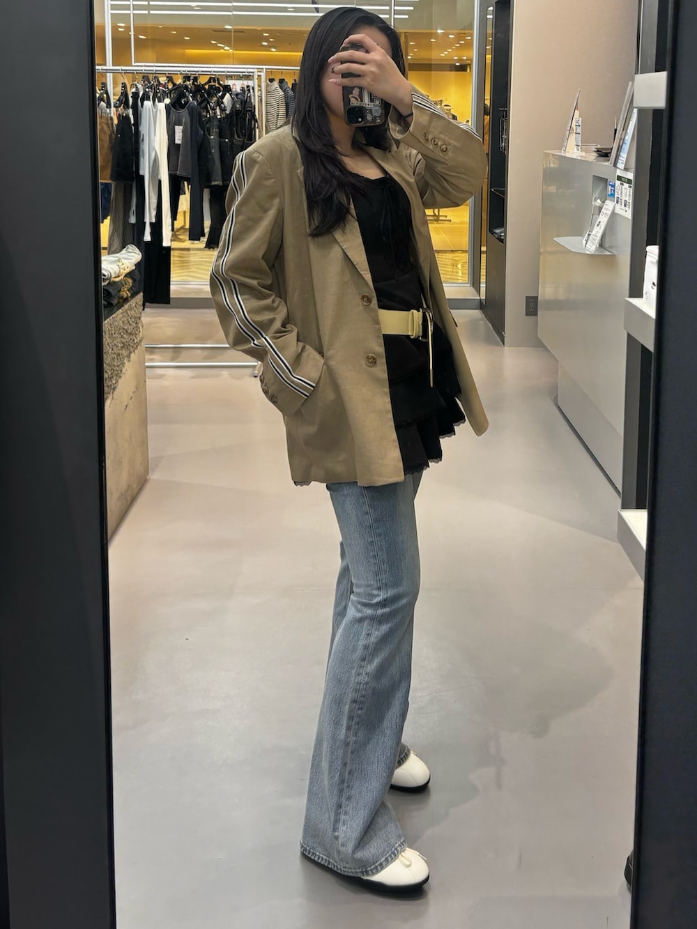 ブラック系のワンピース、グレー系のテーラードジャケット、ブラック系のスニーカーを着用したレディースの春コーディネートの2枚目の写真