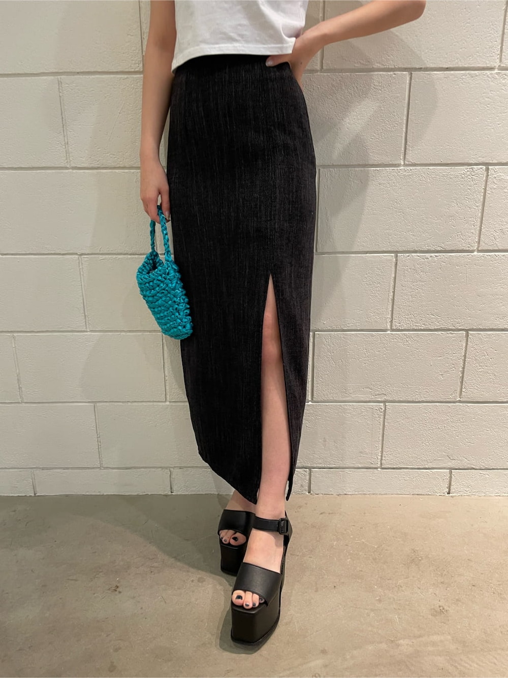 ブラック系のサンダル、ブラック系のスカート、ブルー系のハンドバッグを着用したレディースの春コーディネートの6枚目の写真