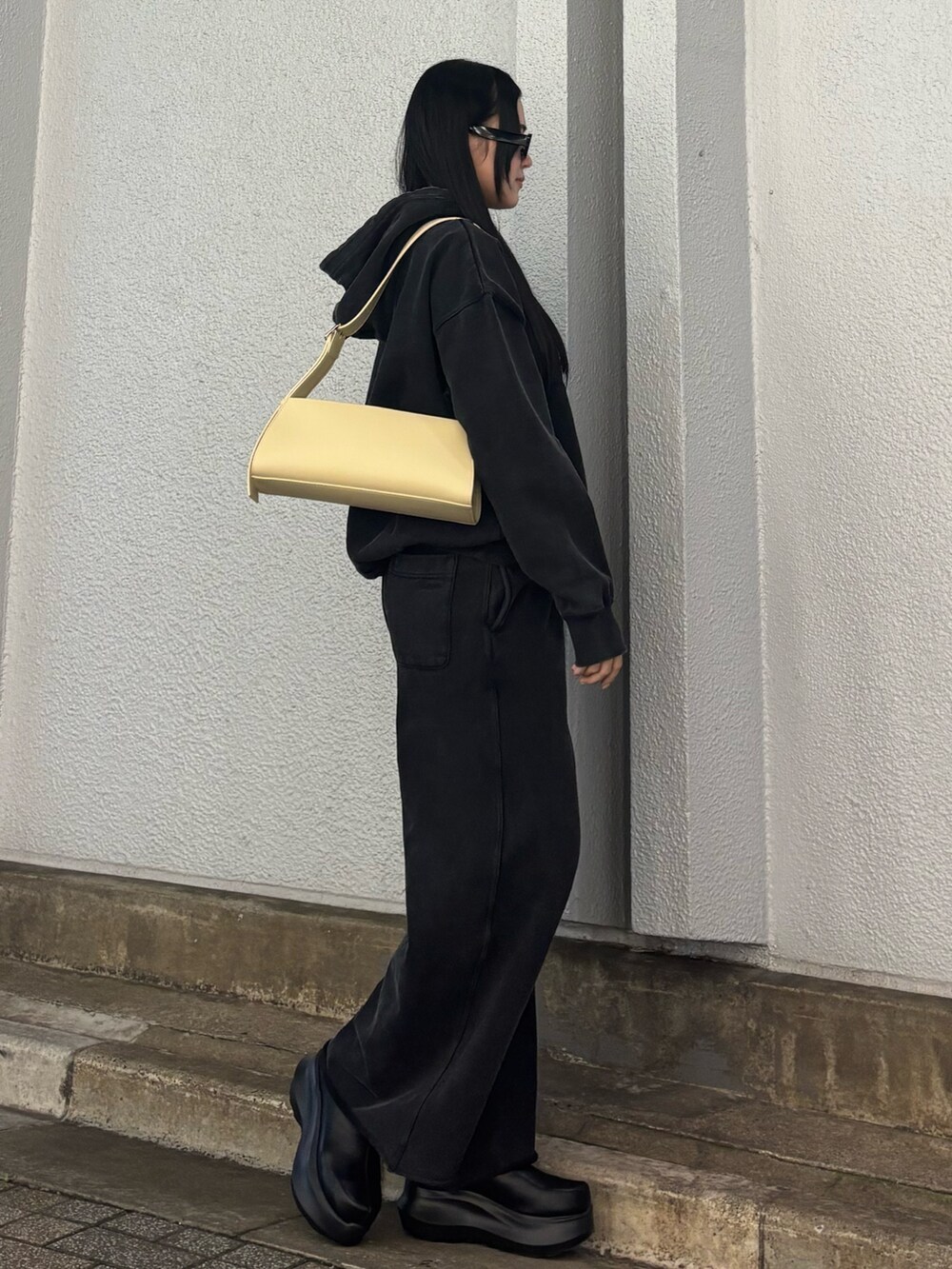 ベージュ系のハンドバッグ、ブラック系のスウェット、ブラック系のスウェットパンツを着用したレディースの秋コーディネートの2枚目の写真
