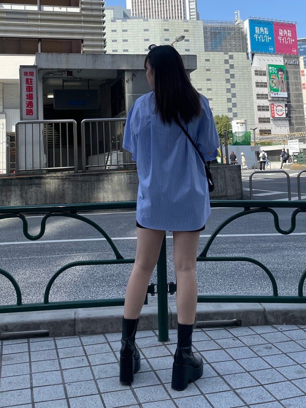 ブラック系のスカート、ブラック系のブーツ、ブラック系のハンドバッグを着用したレディースの春コーディネートの3枚目の写真