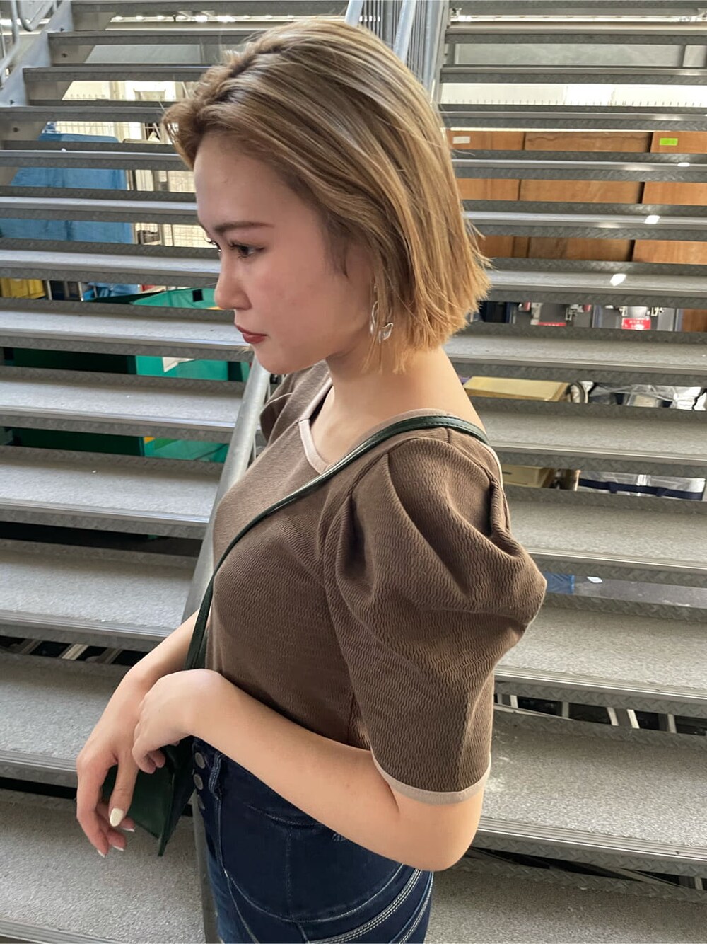 グリーン系のハンドバッグ、ベージュ系のTシャツ/カットソー、ブラック系のサンダルを着用したレディースの夏コーディネートの3枚目の写真