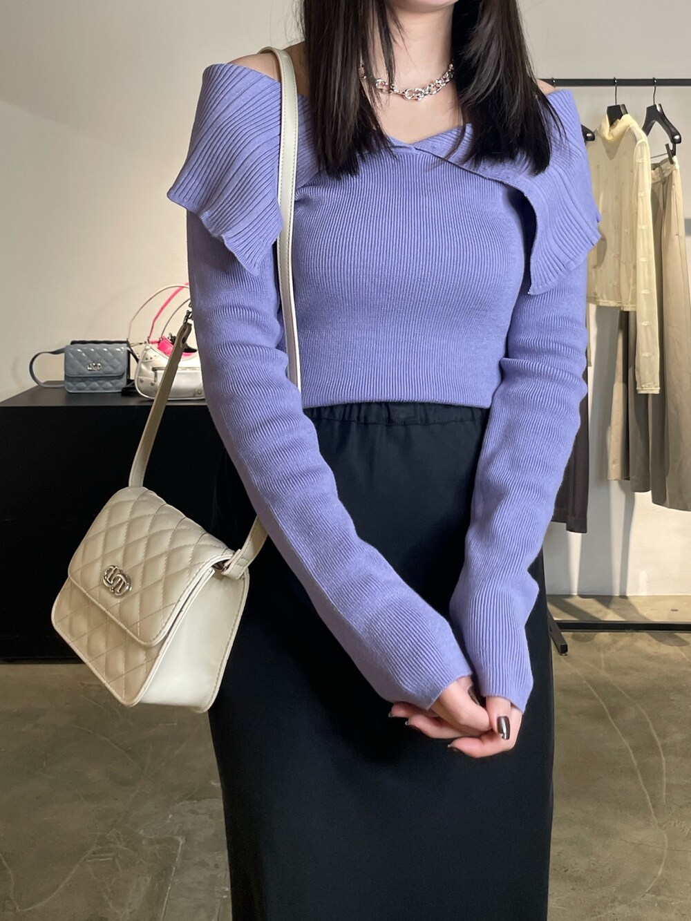 ブラック系のスカート、ブラック系のブーツ、パープル系のニット/セーターを着用したレディースの春コーディネートの4枚目の写真