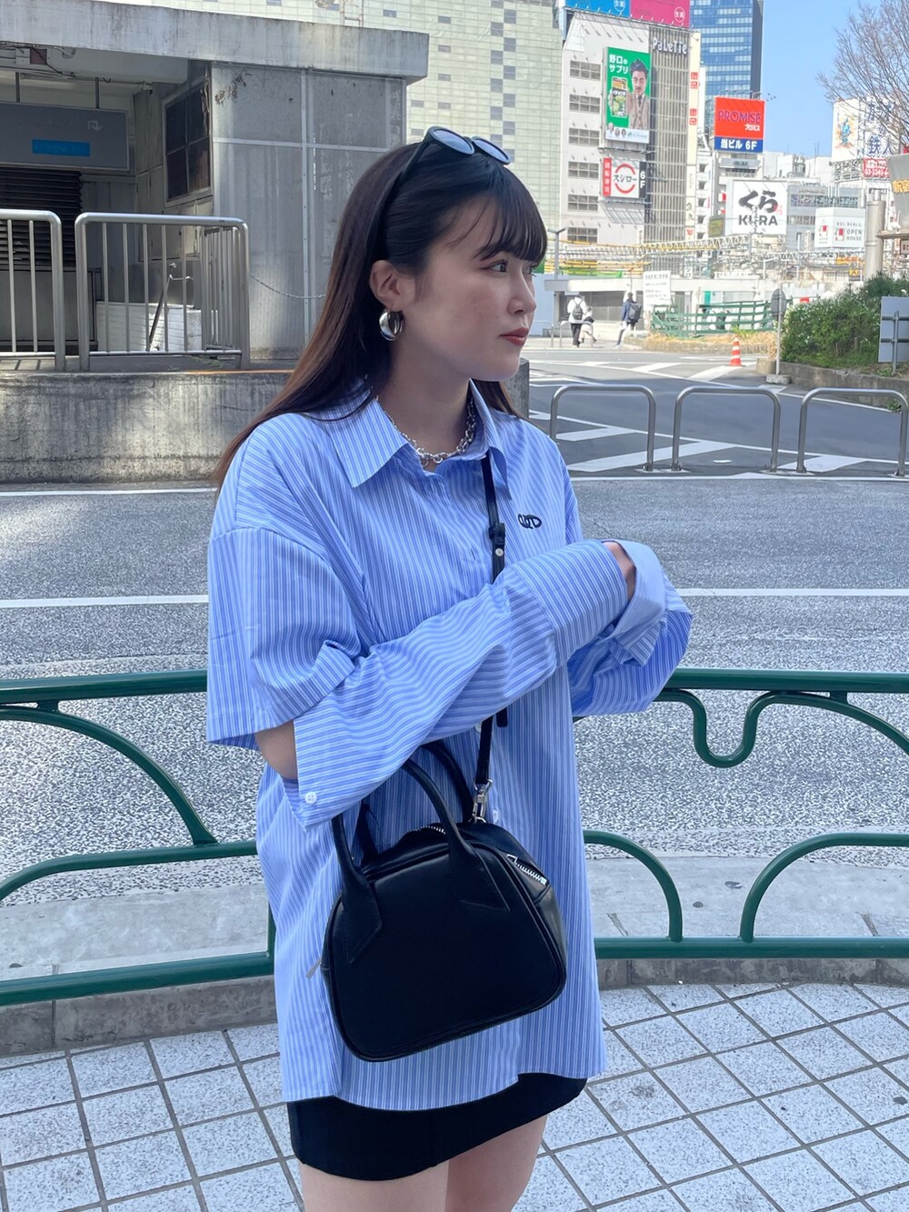 ブラック系のスカート、ブラック系のブーツ、ブラック系のハンドバッグを着用したレディースの春コーディネートの4枚目の写真