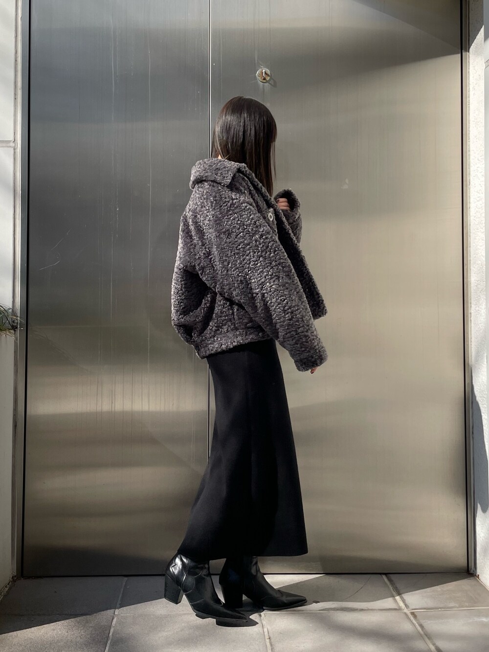 グレー系のブルゾン、ブラック系のワンピース、ブラック系のブーツを着用したレディースの冬コーディネートの2枚目の写真