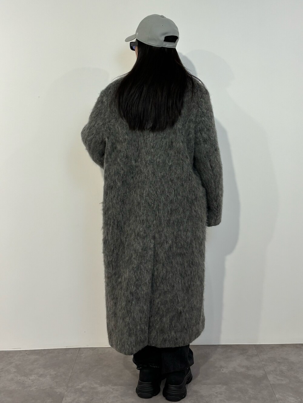 ブラック系のデニムパンツ、ブラック系のスニーカー、グレー系のチェスターコートを着用したレディースの冬コーディネートの5枚目の写真