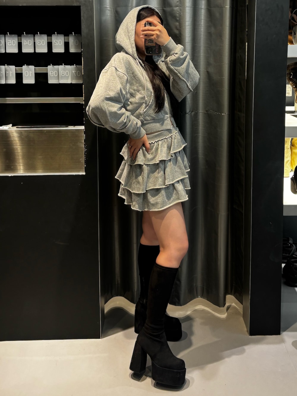 ブラック系のブーツ、ブラック系のパーカー、グレー系のスカートを着用したレディースの秋コーディネートの2枚目の写真