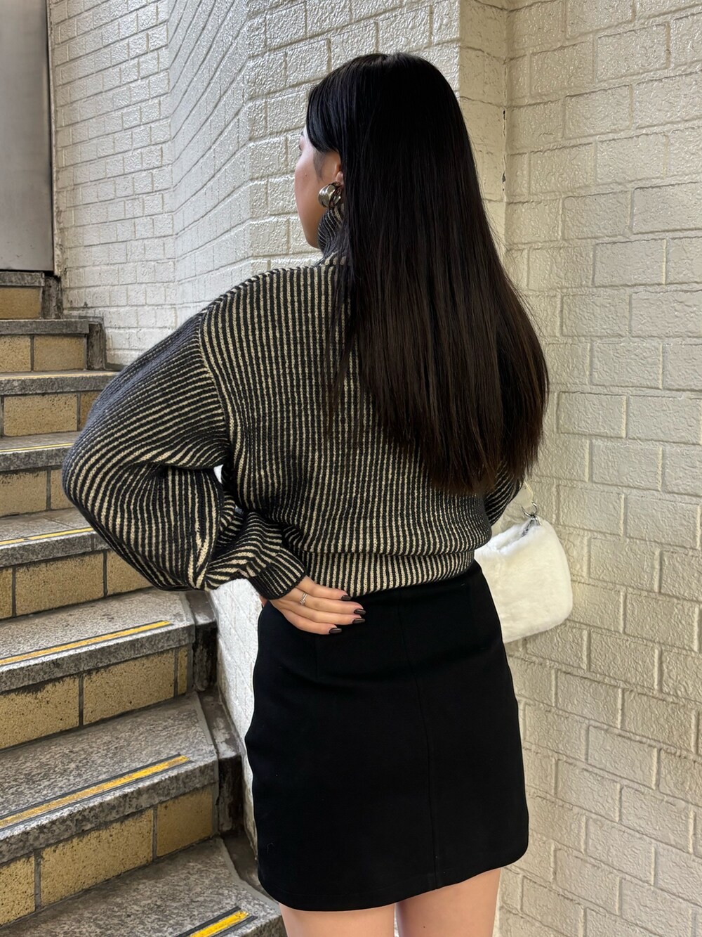 ブラック系のニット/セーター、ブラック系のスカート、その他のブーツを着用したレディースの秋コーディネートの6枚目の写真