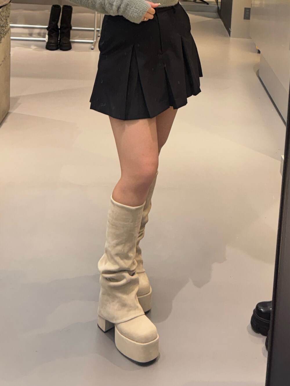 ホワイト系のブーツ、ブラック系のスカート、グレー系のニット/セーターを着用したレディースの秋コーディネートの4枚目の写真