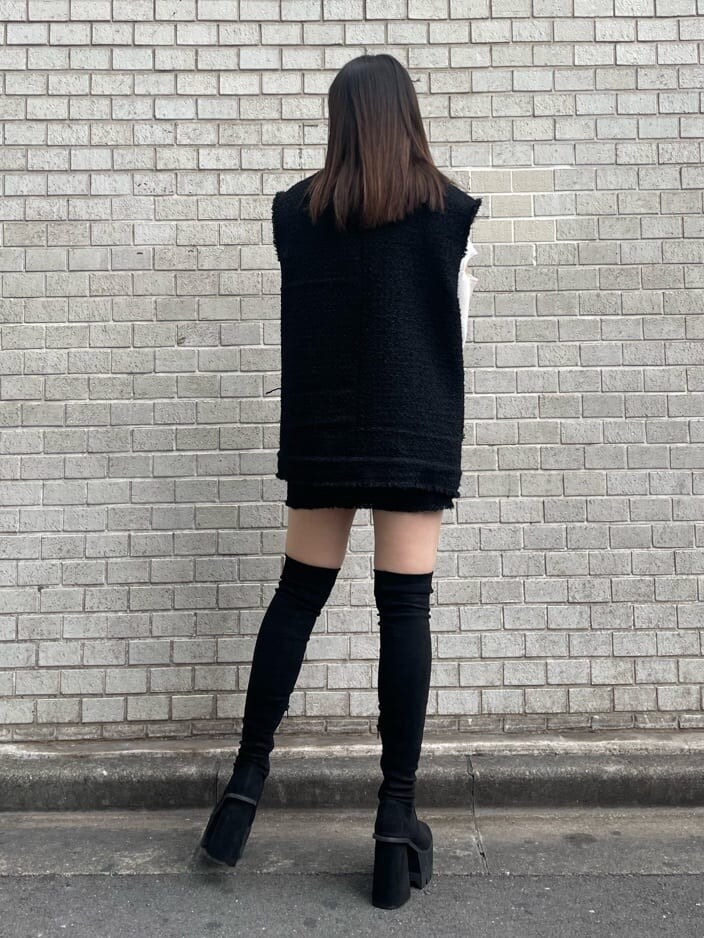 ブラック系のベスト、ブラック系のスカート、ホワイト系のニット/セーターを着用したレディースの秋コーディネートの4枚目の写真