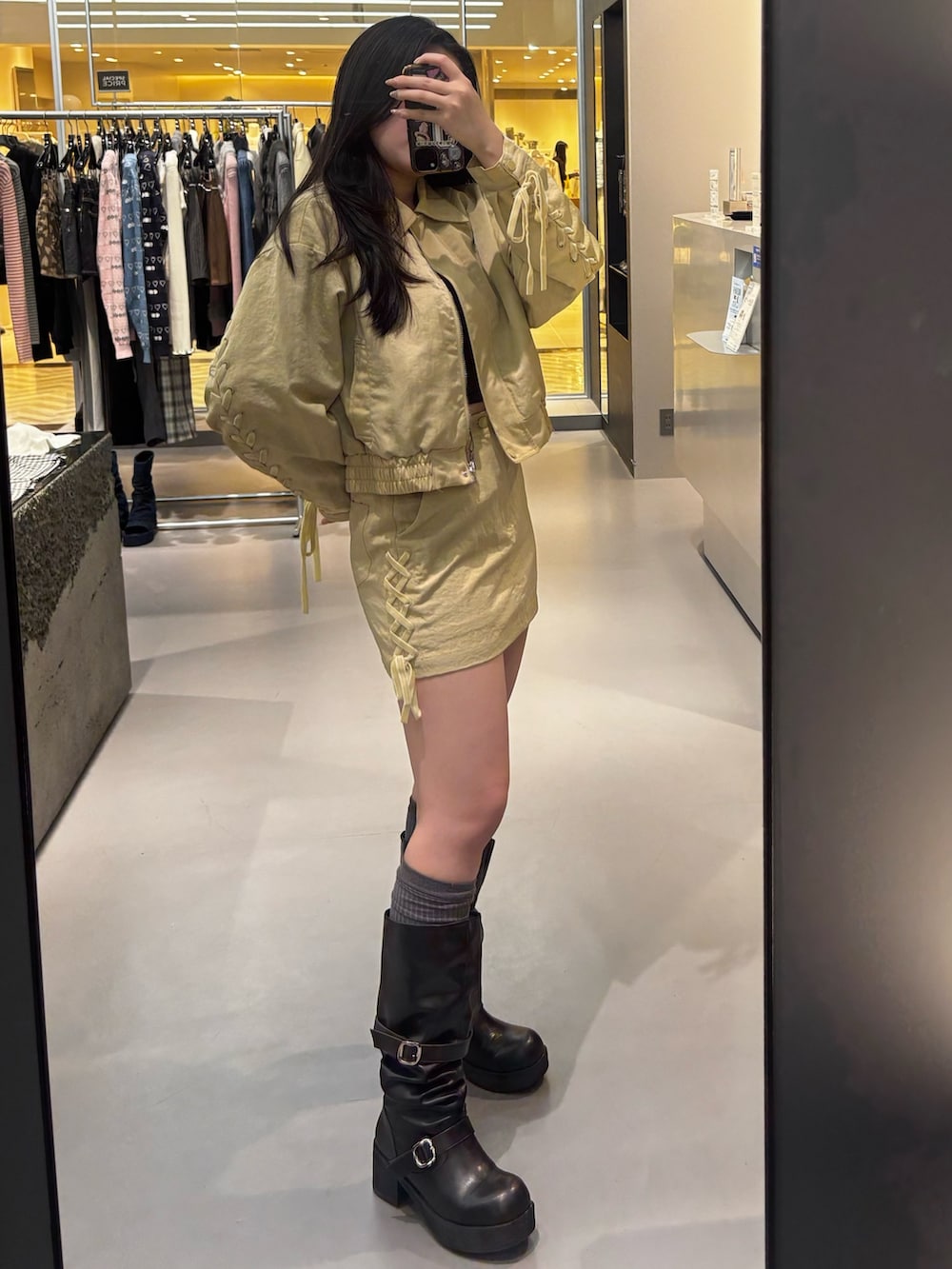 ブラック系のブーツ、イエロー系のスカート、イエロー系のブルゾンを着用したレディースの冬コーディネートの2枚目の写真