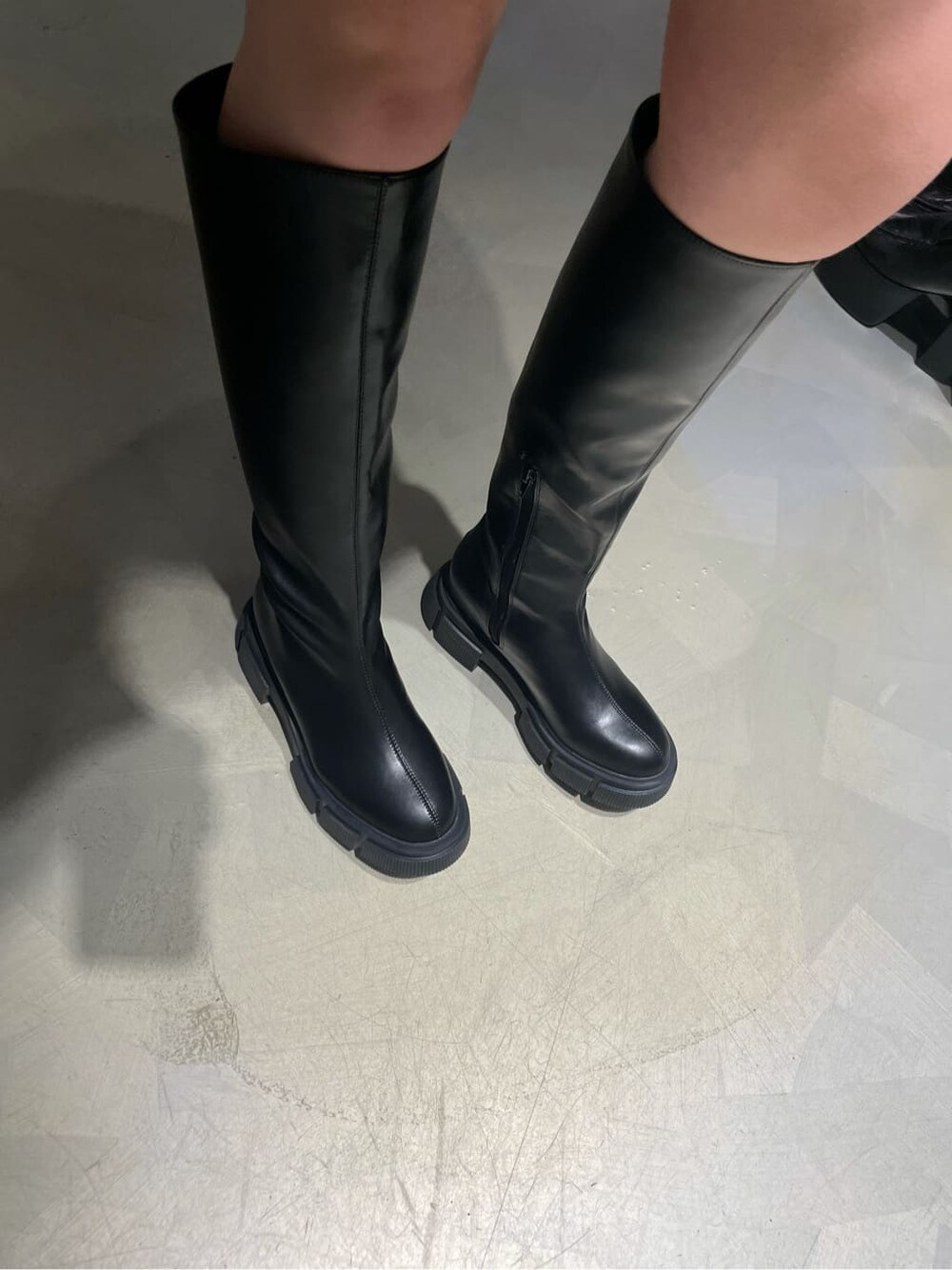 グレー系のスカート、ブラック系のブーツ、ブラック系のカーディガン/ボレロを着用したレディースの冬コーディネートの6枚目の写真