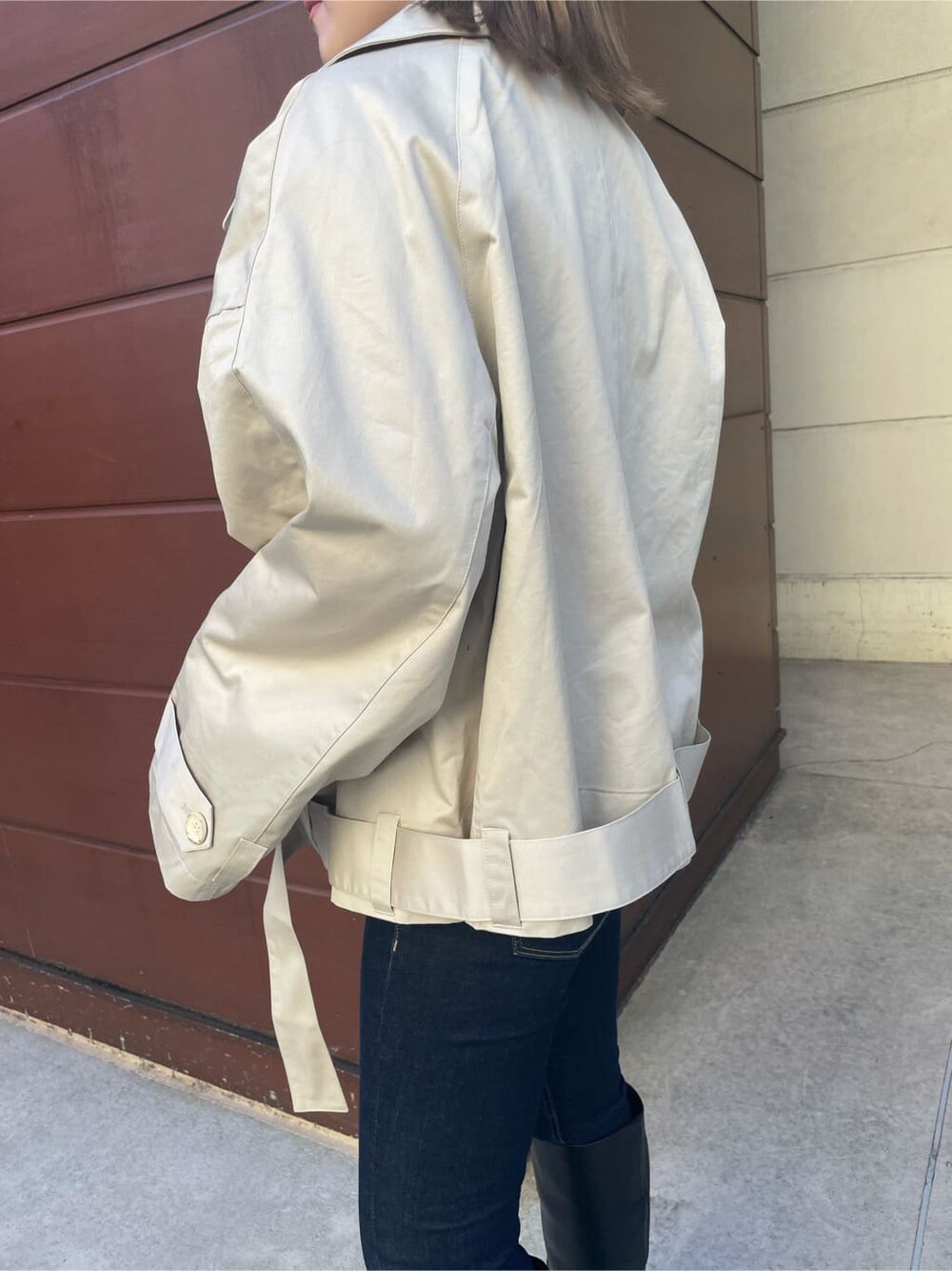 ベージュ系のトレンチコート、ブルー系のデニムパンツ、ブラック系のブーツを着用したレディースの冬コーディネートの3枚目の写真