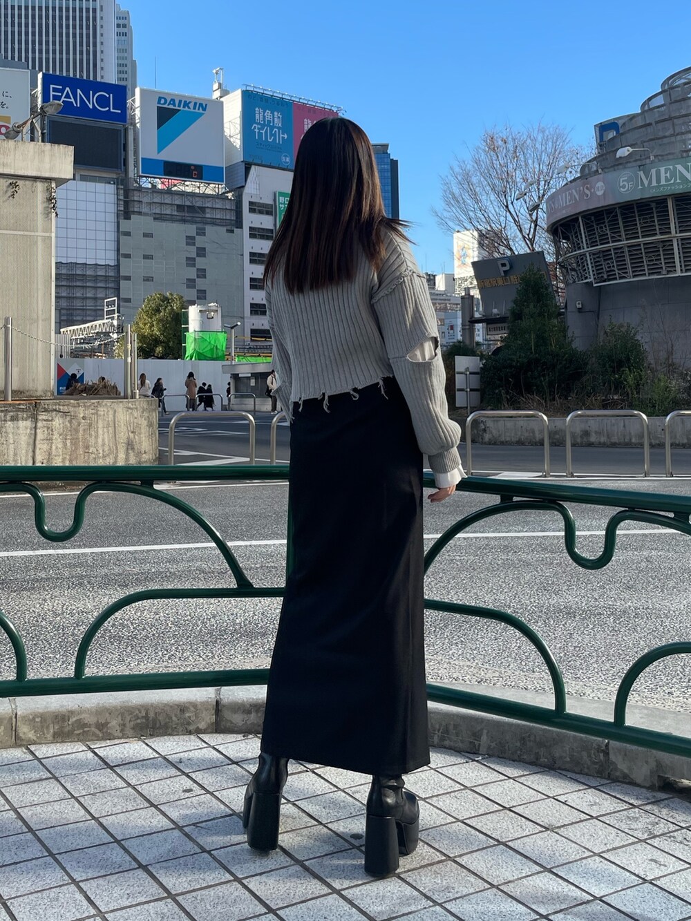 グレー系のニット/セーター、ブラック系のスカート、グリーン系のハンドバッグを着用したレディースの冬コーディネートの3枚目の写真