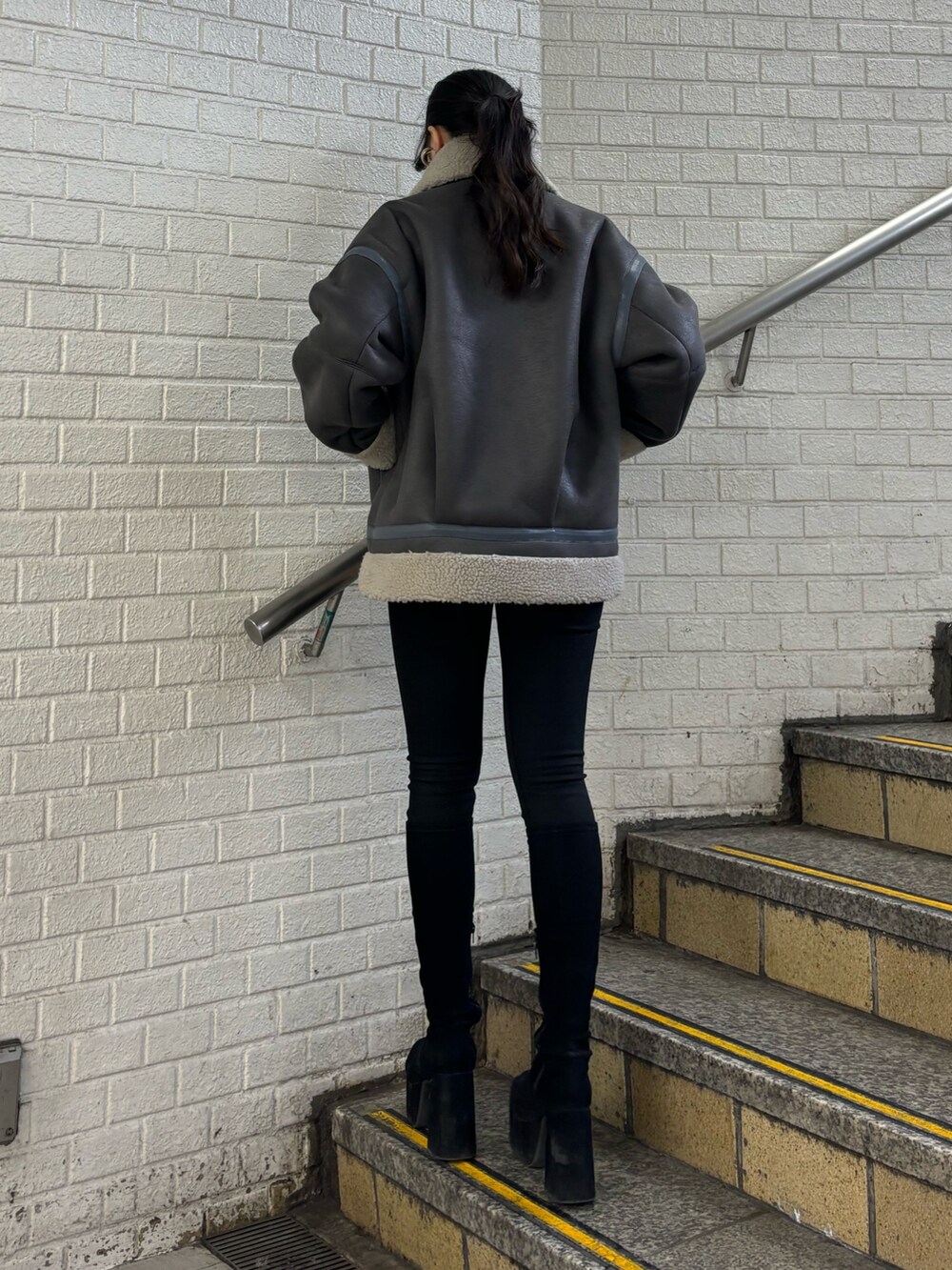 グレー系のムートンコート、ブラック系のデニムパンツ、その他のブーツを着用したレディースの秋コーディネートの3枚目の写真