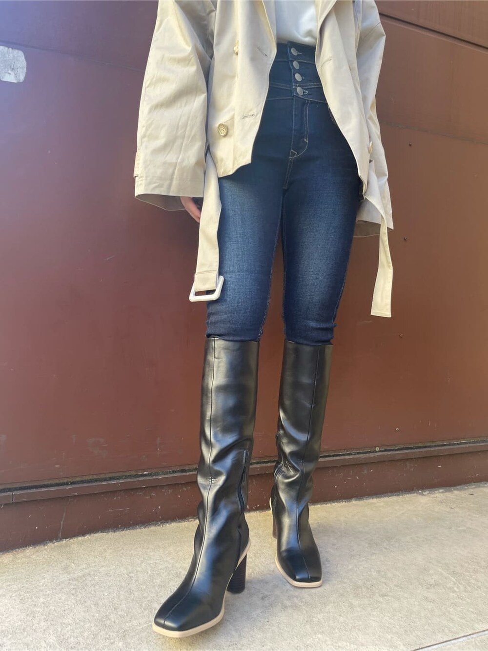 ベージュ系のトレンチコート、ブルー系のデニムパンツ、ブラック系のブーツを着用したレディースの冬コーディネートの6枚目の写真
