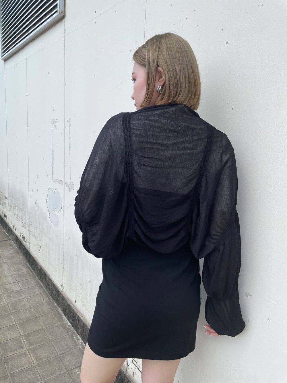 ブラック系のスカート、ブラック系のサンダル、ホワイト系のニット/セーターを着用したレディースの秋コーディネートの7枚目の写真