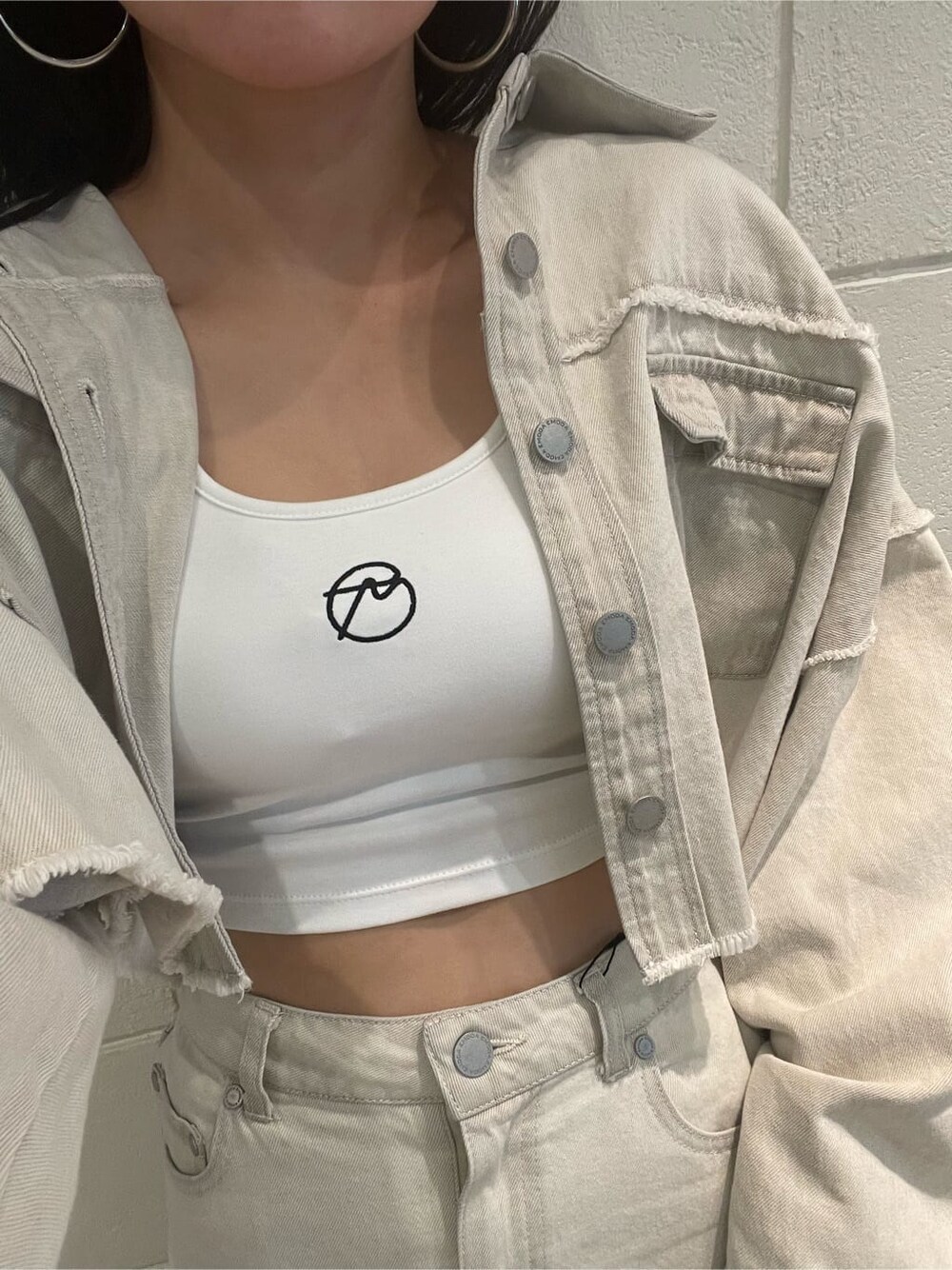 ホワイト系のデニムジャケット、ホワイト系のタンクトップ、ブラック系のブーツを着用したレディースの夏コーディネートの6枚目の写真