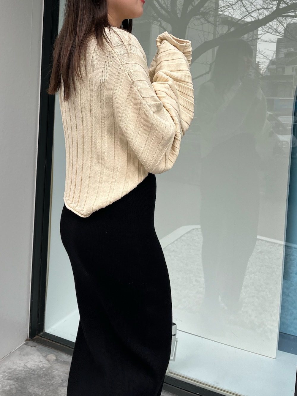 ホワイト系のニット/セーター、ベージュ系のブーツ、ブラック系のワンピースを着用したレディースの春コーディネートの5枚目の写真