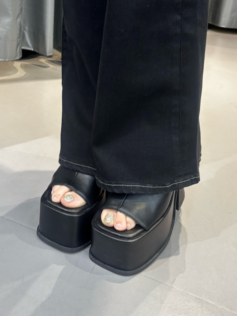ブラック系のサンダル、ブラック系のデニムパンツ、ブラック系のタンクトップを着用したレディースの夏コーディネートの5枚目の写真