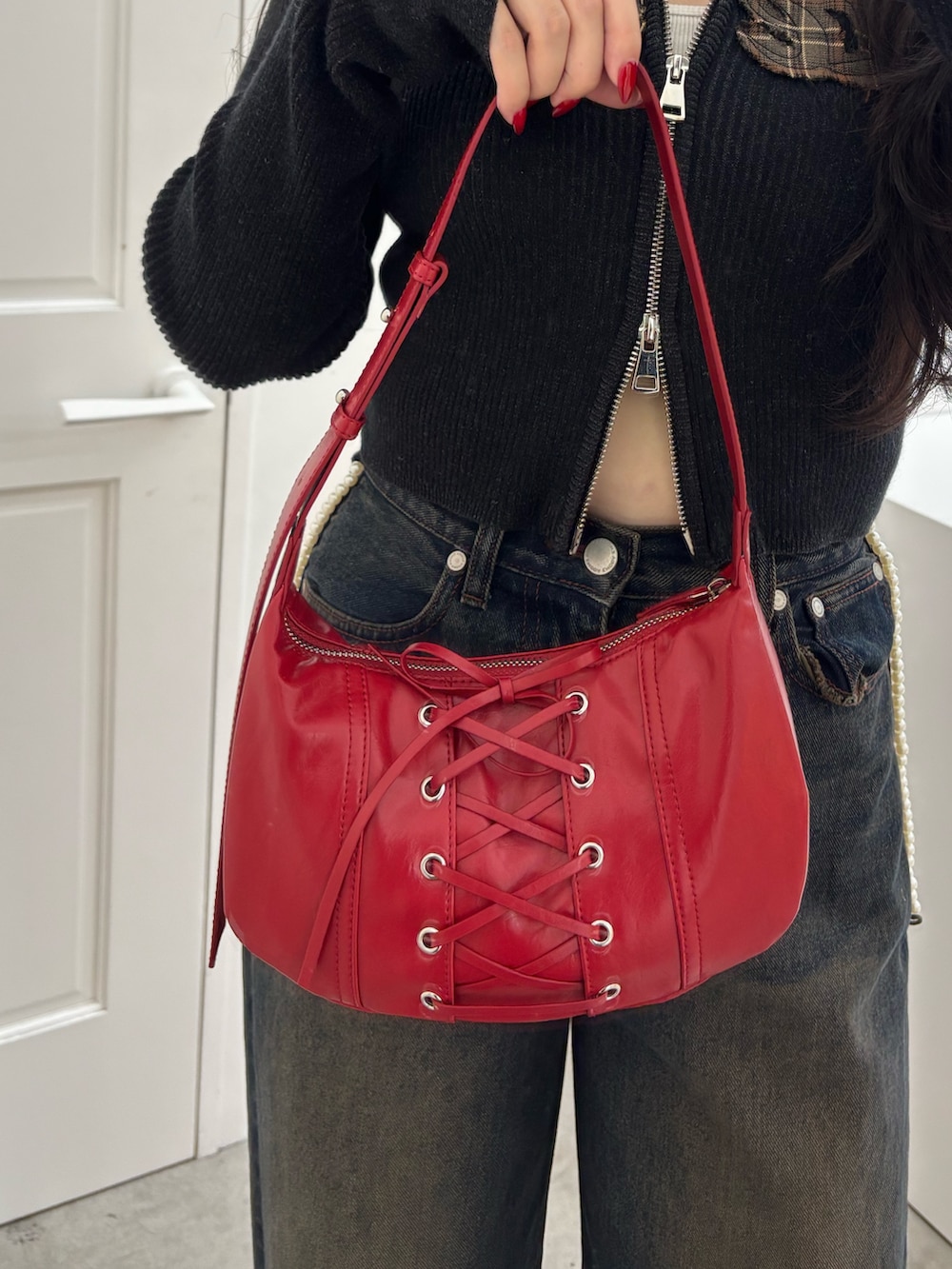 ブラック系のブーツ、ブルー系のデニムパンツ、レッド系のショルダーバッグを着用したレディースの秋コーディネートの4枚目の写真