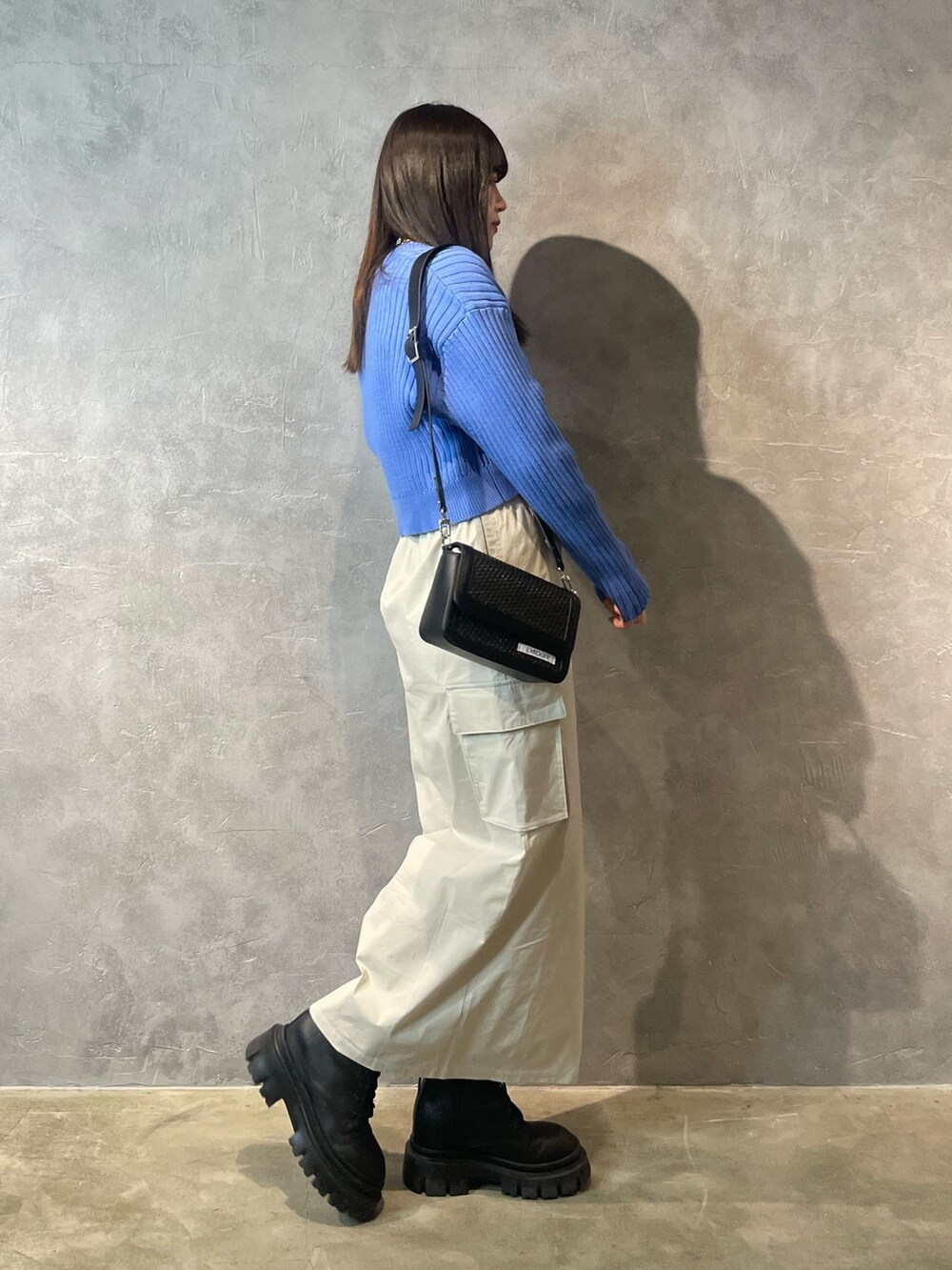 ホワイト系のスカート、ブラック系のブーツ、ブルー系のカーディガン/ボレロを着用したレディースの春コーディネートの2枚目の写真