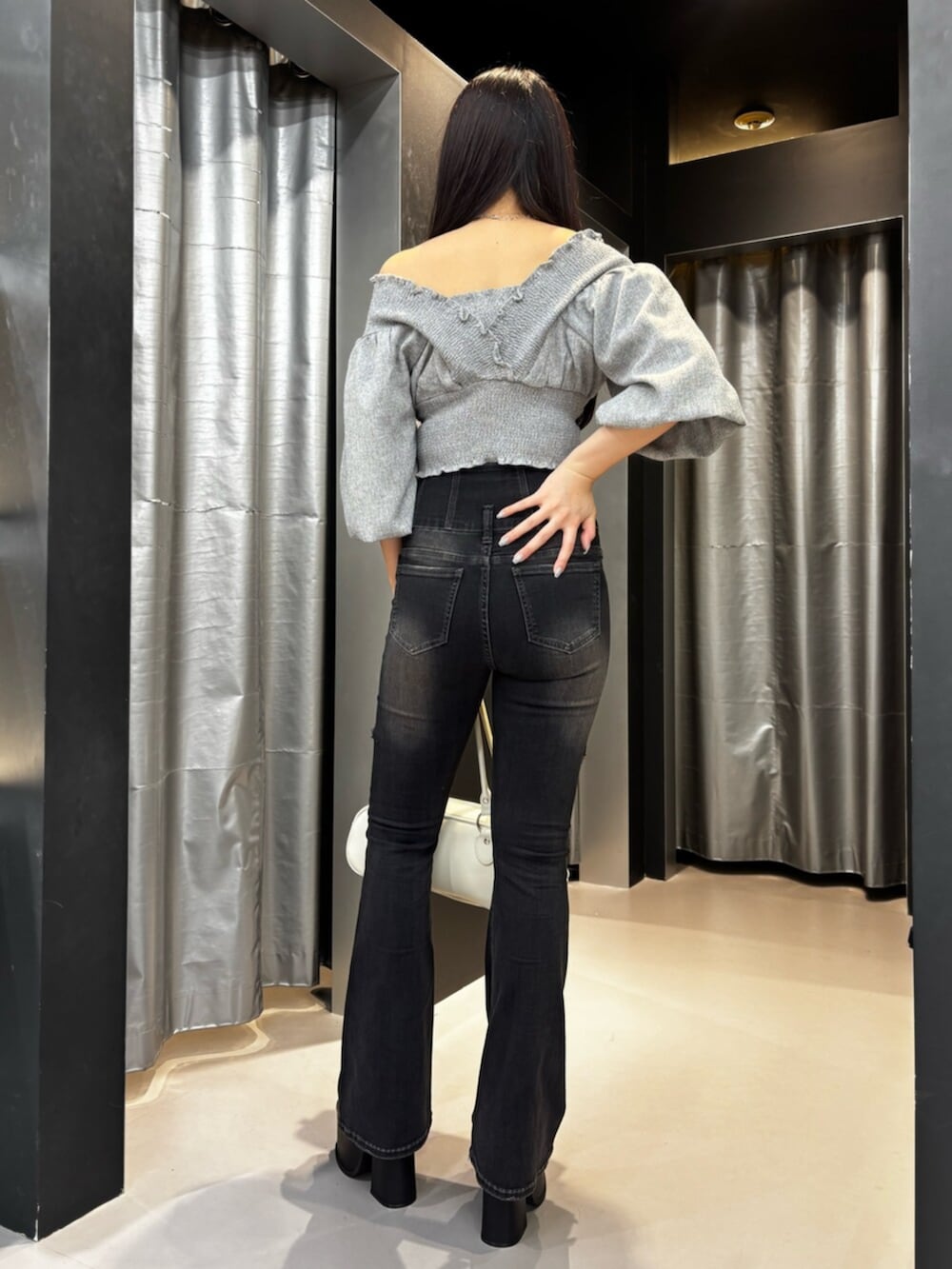ホワイト系のハンドバッグ、ブラック系のサンダル、ブラック系のデニムパンツを着用したレディースの夏コーディネートの2枚目の写真
