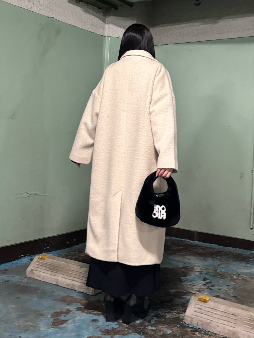 ホワイト系のチェスターコート、ブラック系のブーツ、ブラック系のハンドバッグを着用したレディースの冬コーディネートの3枚目の写真