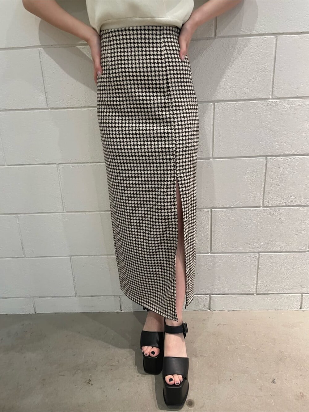 ブラック系のサンダル、ホワイト系のニット/セーター、その他のスカートを着用したレディースの春コーディネートの6枚目の写真