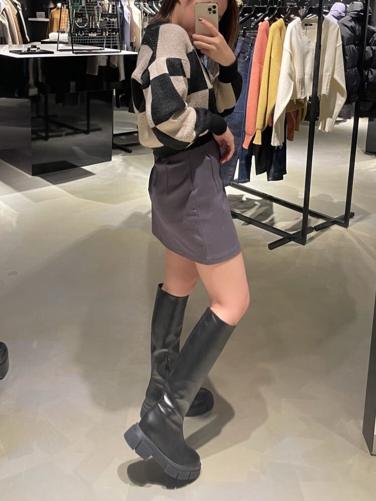 グレー系のスカート、ブラック系のブーツ、ブラック系のカーディガン/ボレロを着用したレディースの冬コーディネートの2枚目の写真