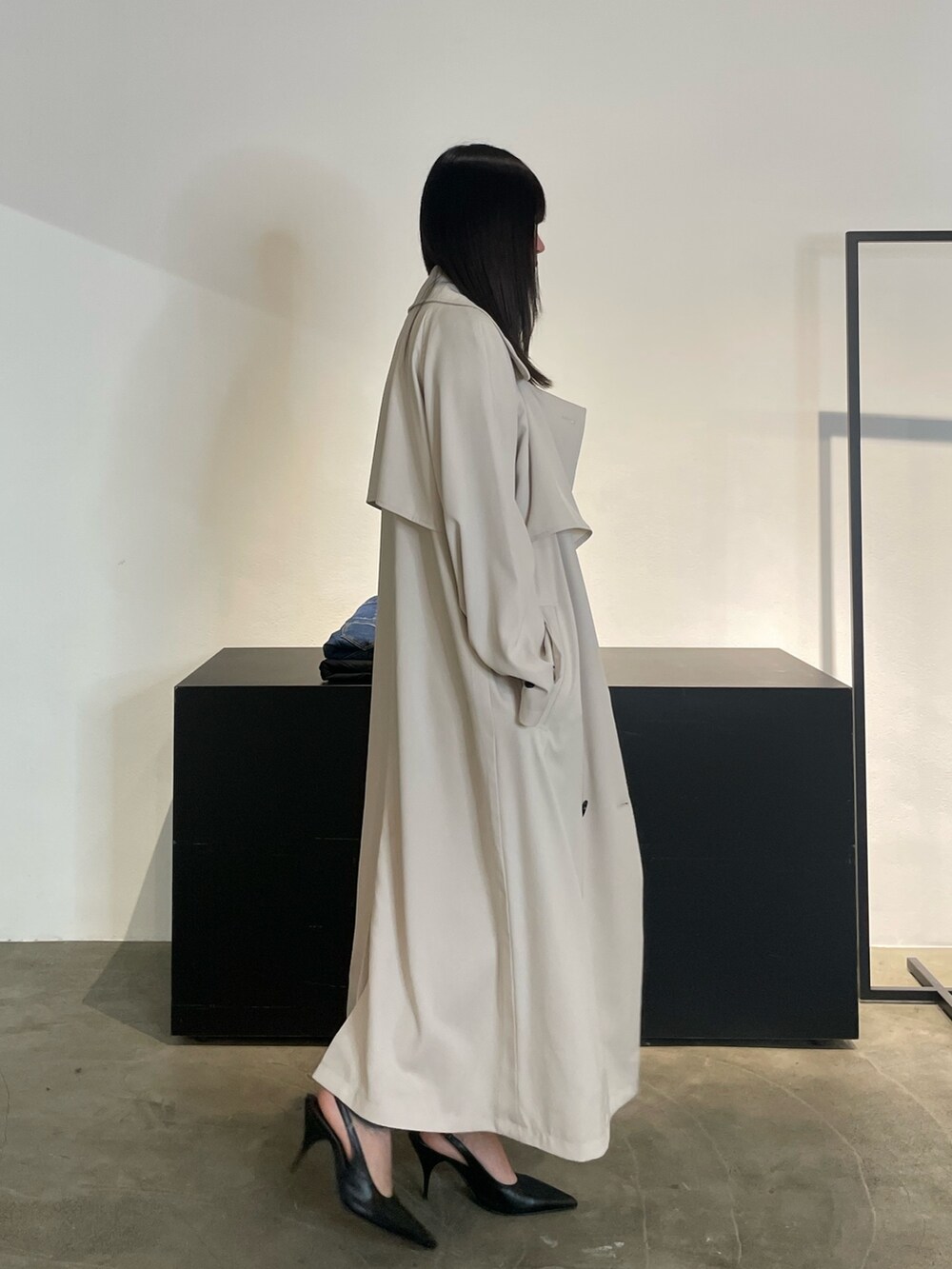 グリーン系のトレンチコート、ブラック系のパンプス、ブルー系のデニムパンツを着用したレディースの冬コーディネートの3枚目の写真