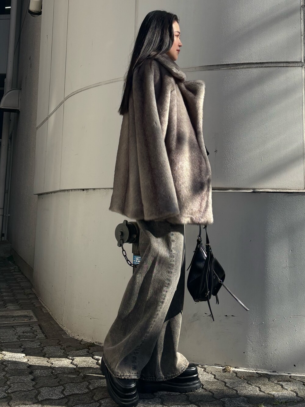 グレー系のその他アウター、ブラック系のニット/セーター、ブラック系のハンドバッグを着用したレディースの冬コーディネートの2枚目の写真