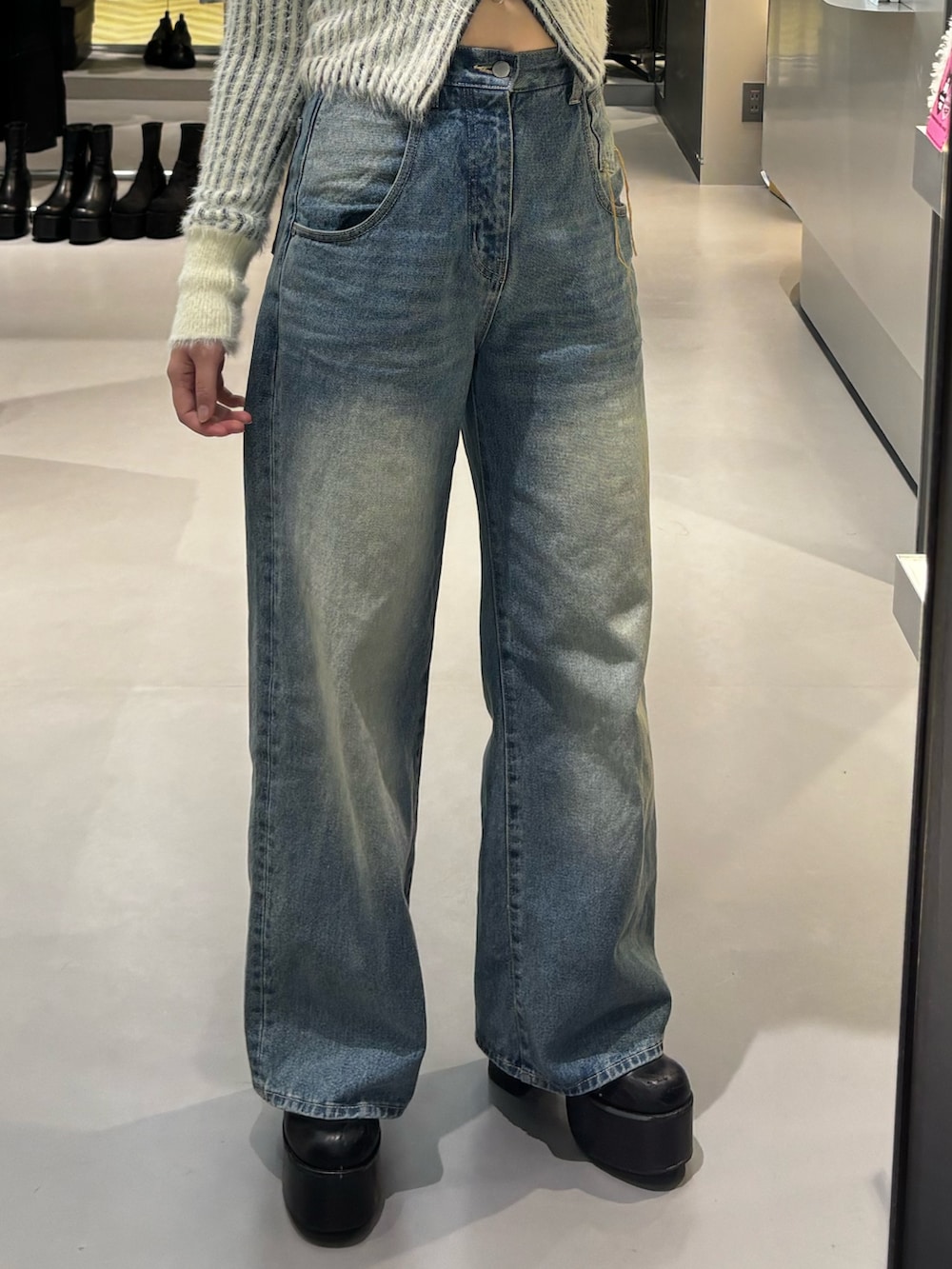 ブルー系のデニムパンツ、ブラック系のニット/セーター、ブラック系のブーツを着用したレディースの冬コーディネートの6枚目の写真