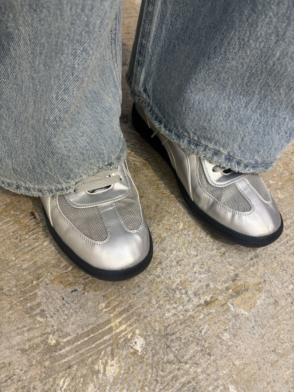 シルバー系のスニーカー、ブルー系のデニムパンツ、ブラック系のニット/セーターを着用したレディースの春コーディネートの6枚目の写真