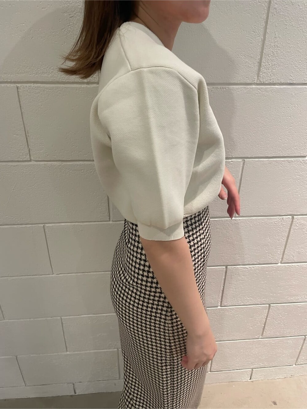 ブラック系のサンダル、ホワイト系のニット/セーター、その他のスカートを着用したレディースの春コーディネートの5枚目の写真