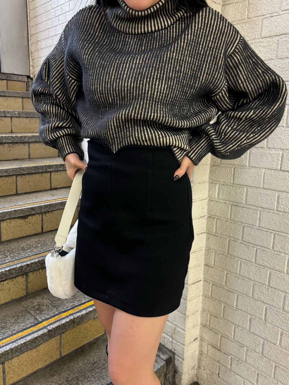 ブラック系のニット/セーター、ブラック系のスカート、その他のブーツを着用したレディースの秋コーディネートの4枚目の写真