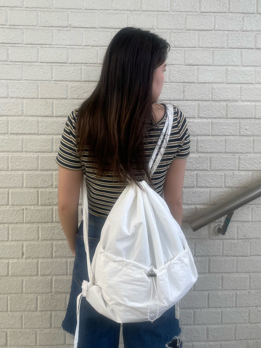 ブラック系のデニムパンツ、その他のTシャツ/カットソー、ホワイト系のバックパック/リュックを着用したレディースの夏コーディネートの5枚目の写真