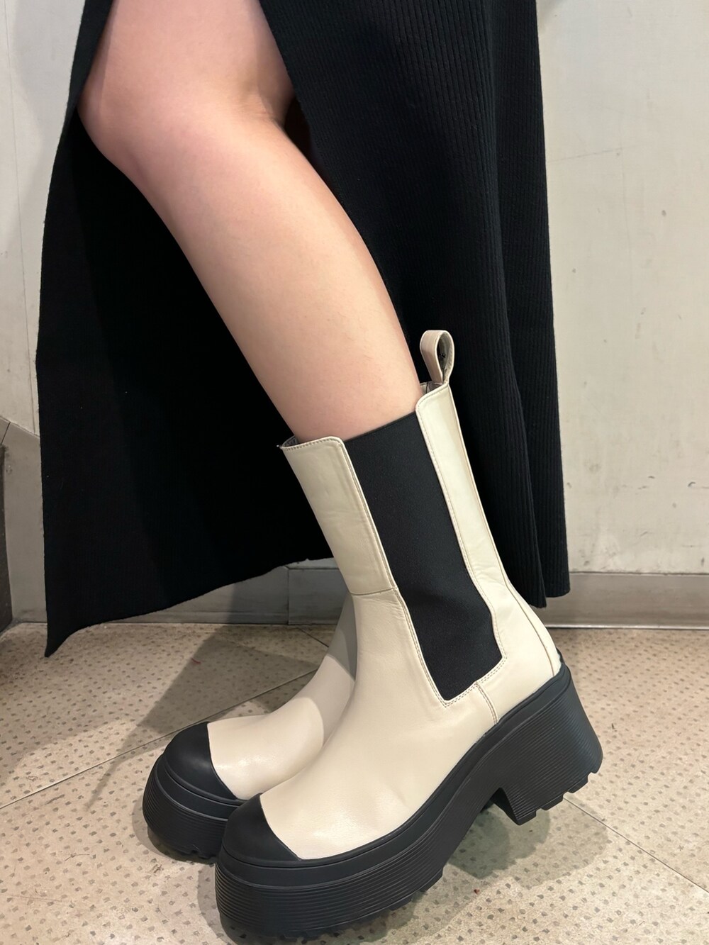 ブラック系のムートンコート、ブラック系のワンピース、ホワイト系のブーツを着用したレディースの秋コーディネートの9枚目の写真