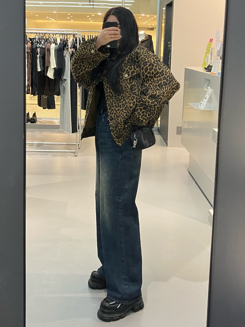 ブラック系のハンドバッグ、ブルー系のデニムパンツ、ベージュ系のブルゾンを着用したレディースの秋コーディネートの2枚目の写真