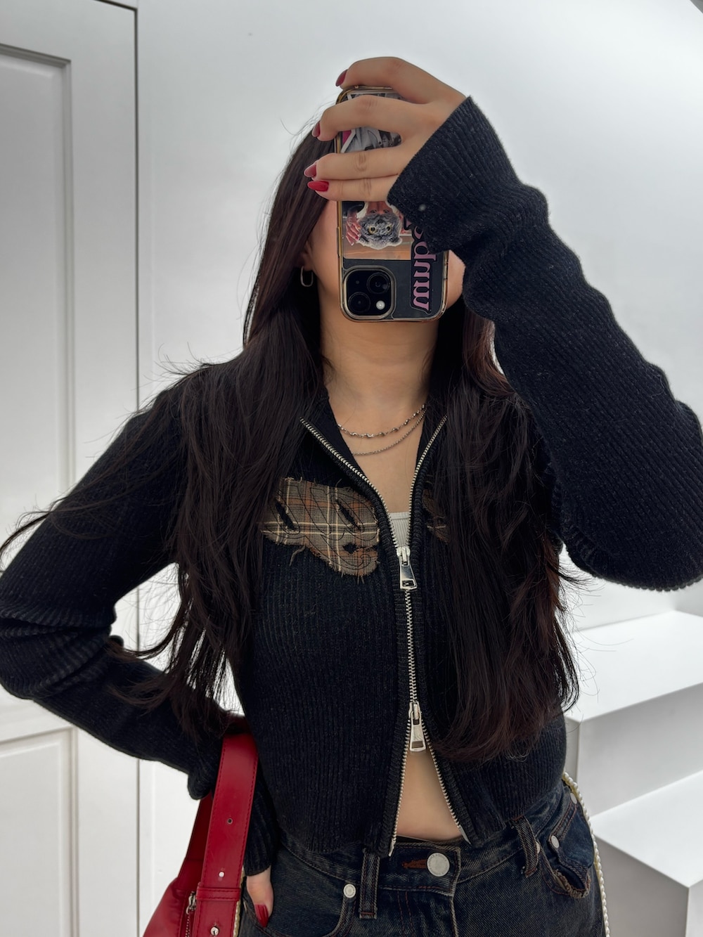 ブラック系のブーツ、ブルー系のデニムパンツ、レッド系のショルダーバッグを着用したレディースの秋コーディネートの3枚目の写真