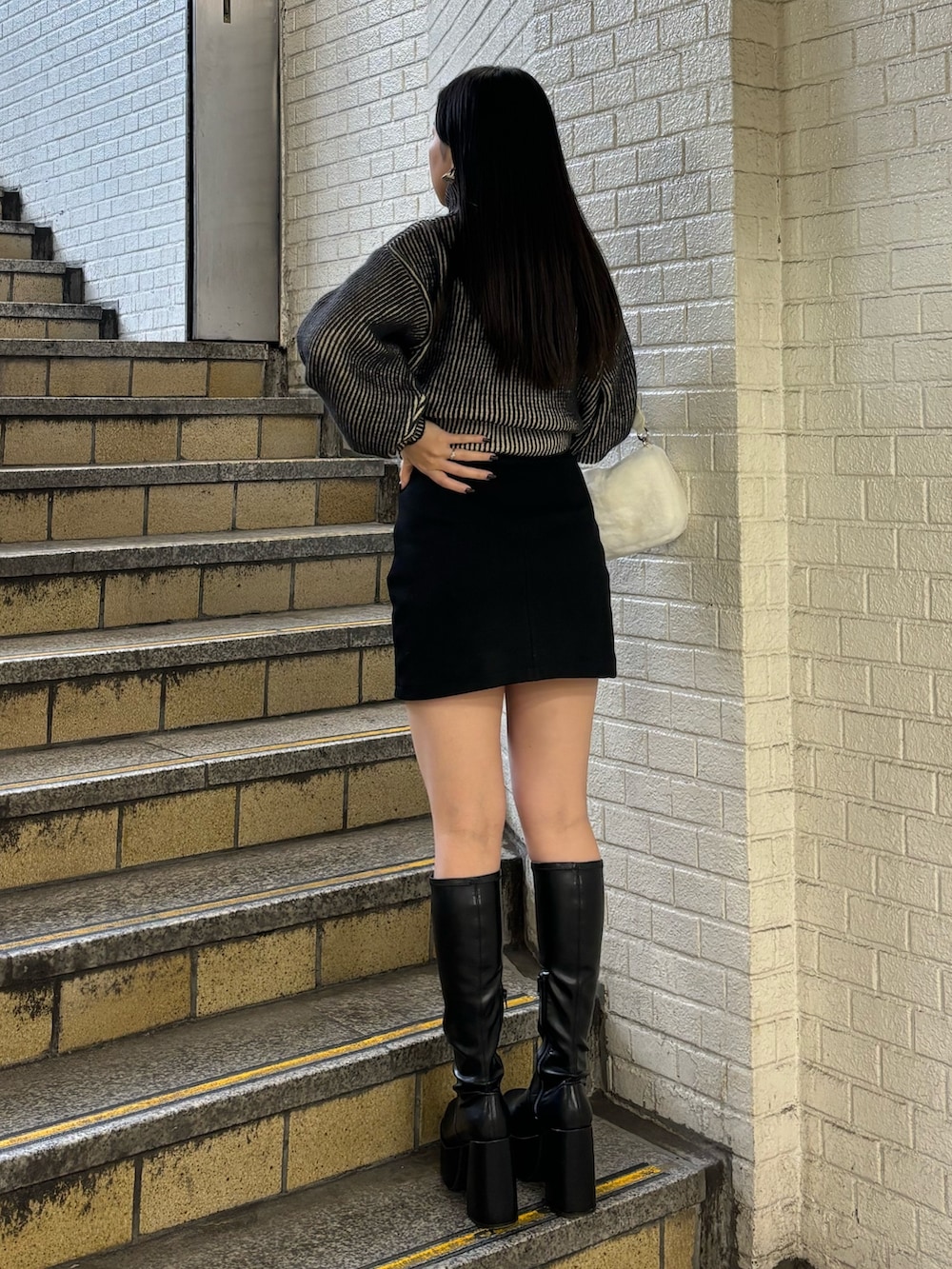 ブラック系のニット/セーター、ブラック系のスカート、その他のブーツを着用したレディースの秋コーディネートの3枚目の写真