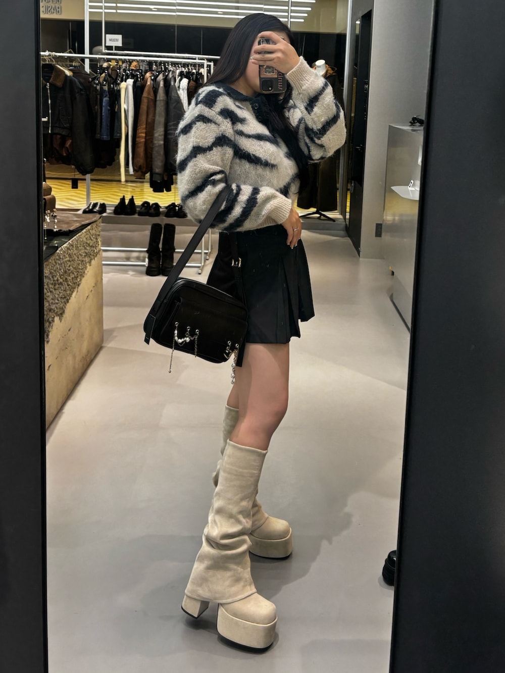 ホワイト系のブーツ、ホワイト系のニット/セーター、ブラック系のスカートを着用したレディースの秋コーディネートの2枚目の写真