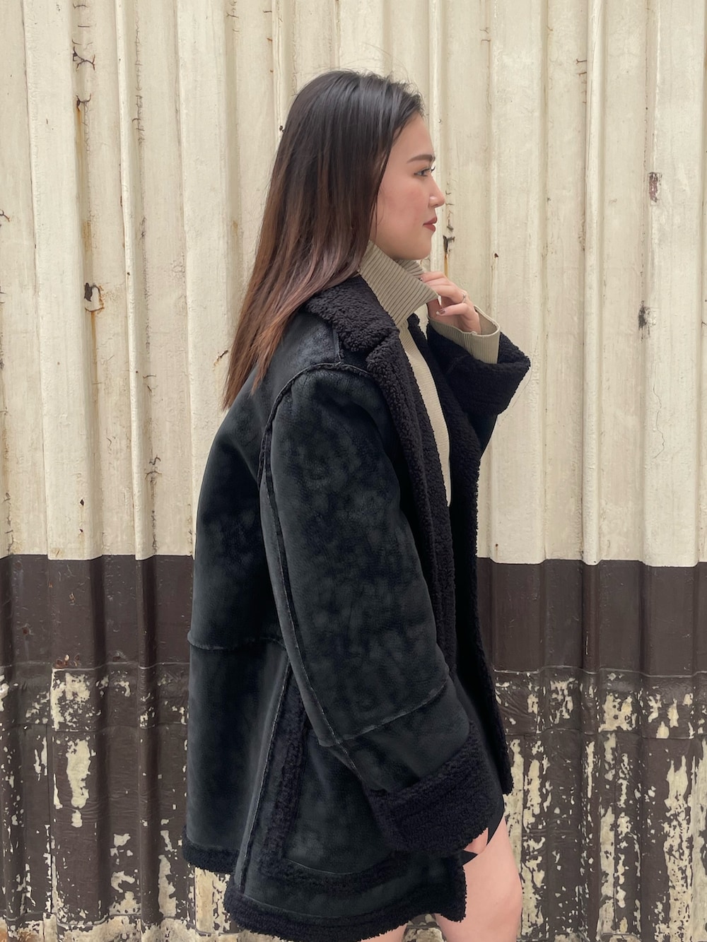 ブラック系のムートンコート、ブラック系のスカート、ホワイト系のブーツを着用したレディースの冬コーディネートの5枚目の写真