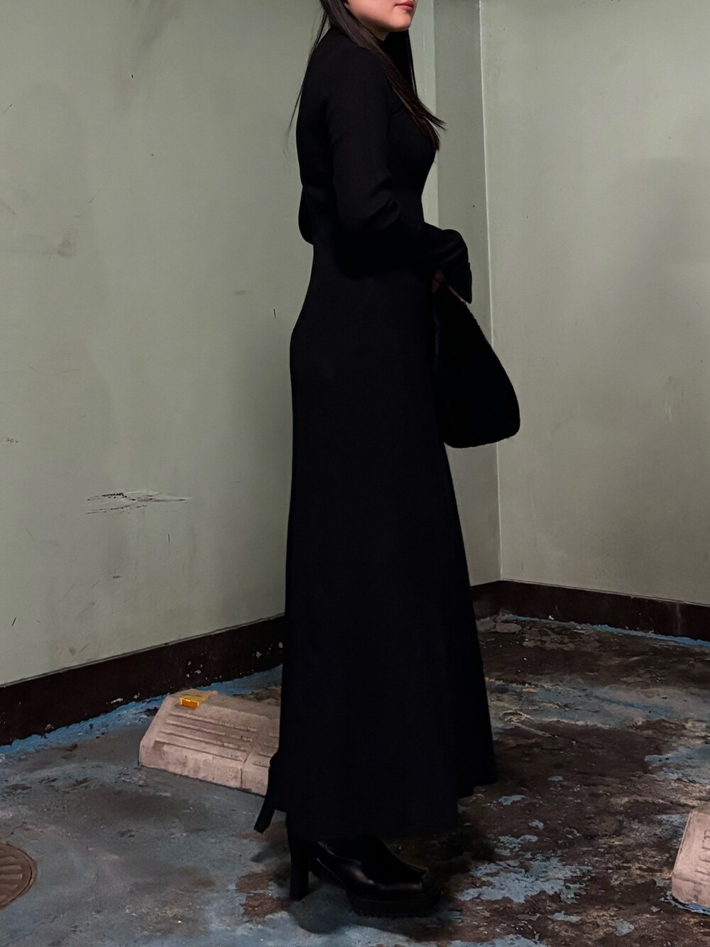 ブラック系のハンドバッグ、ブラック系のワンピース、ブラック系のブーツを着用したレディースの冬コーディネートの2枚目の写真