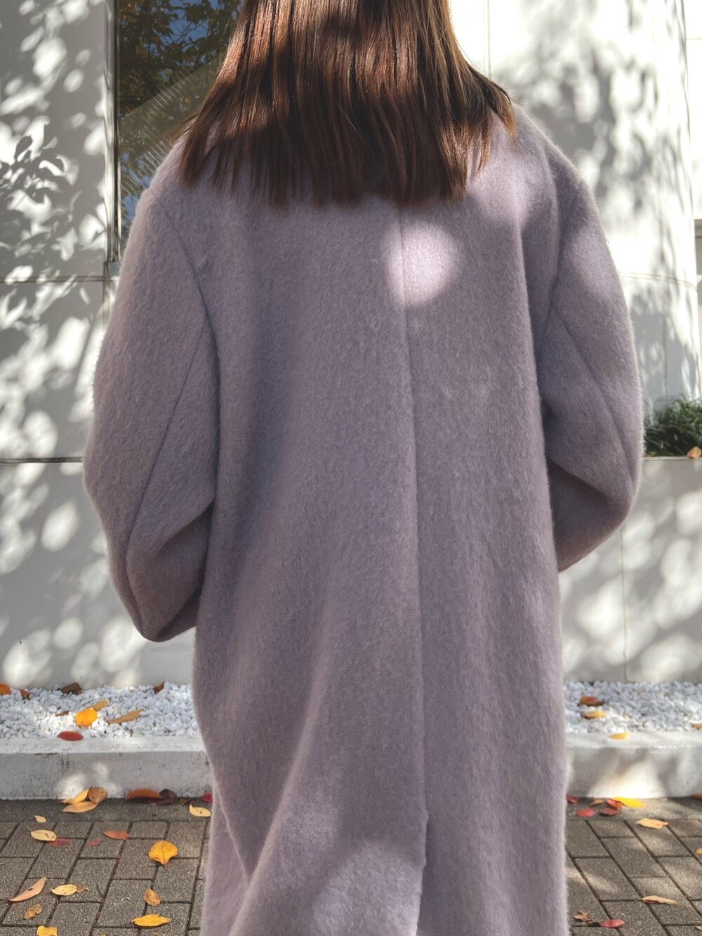 パープル系のチェスターコート、ブラック系のワンピース、ブラック系のブーツを着用したレディースの冬コーディネートの6枚目の写真