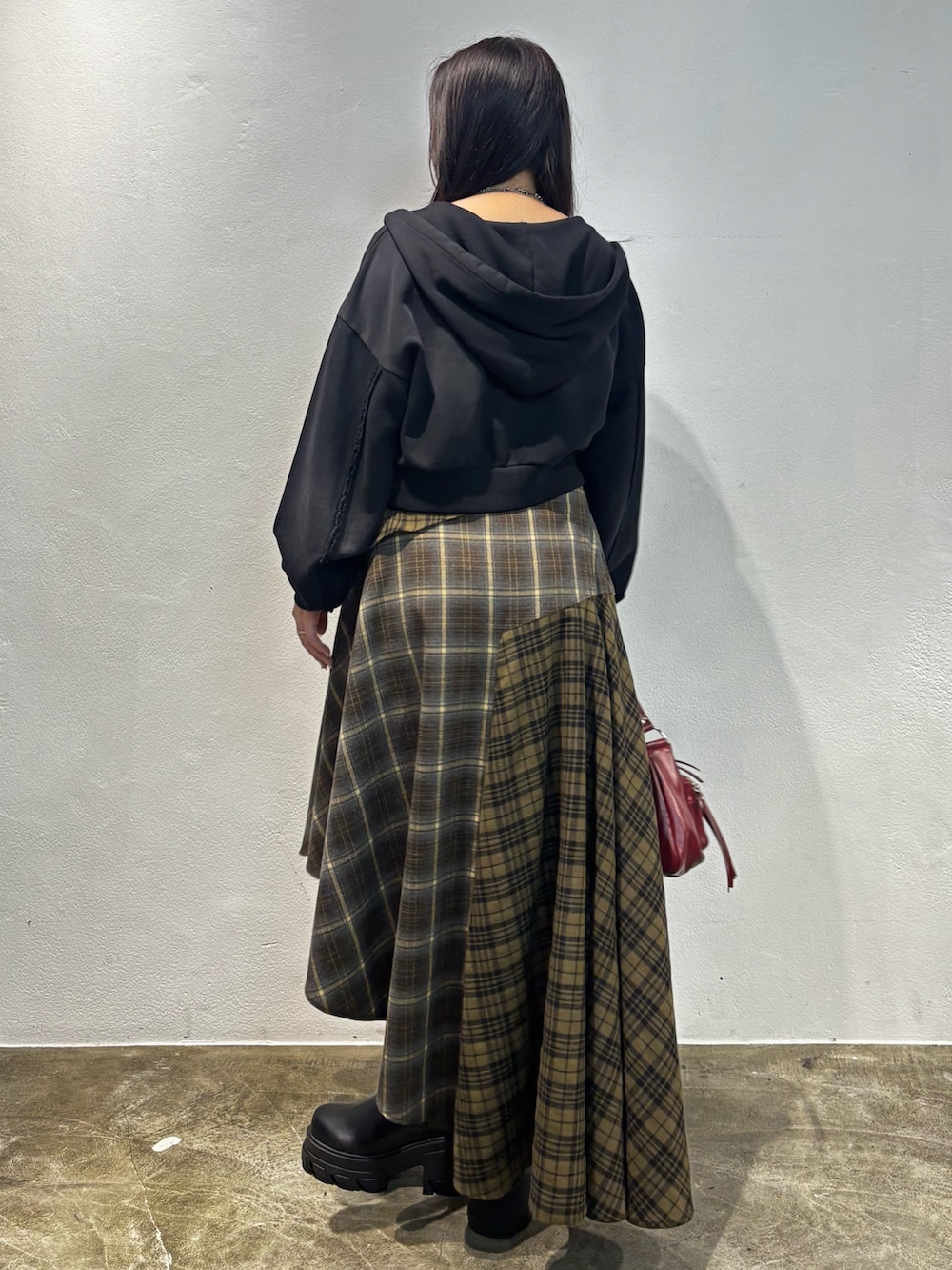 ブラウン系のブーツ、グリーン系のスカート、ブラック系のパーカーを着用したレディースの秋コーディネートの3枚目の写真