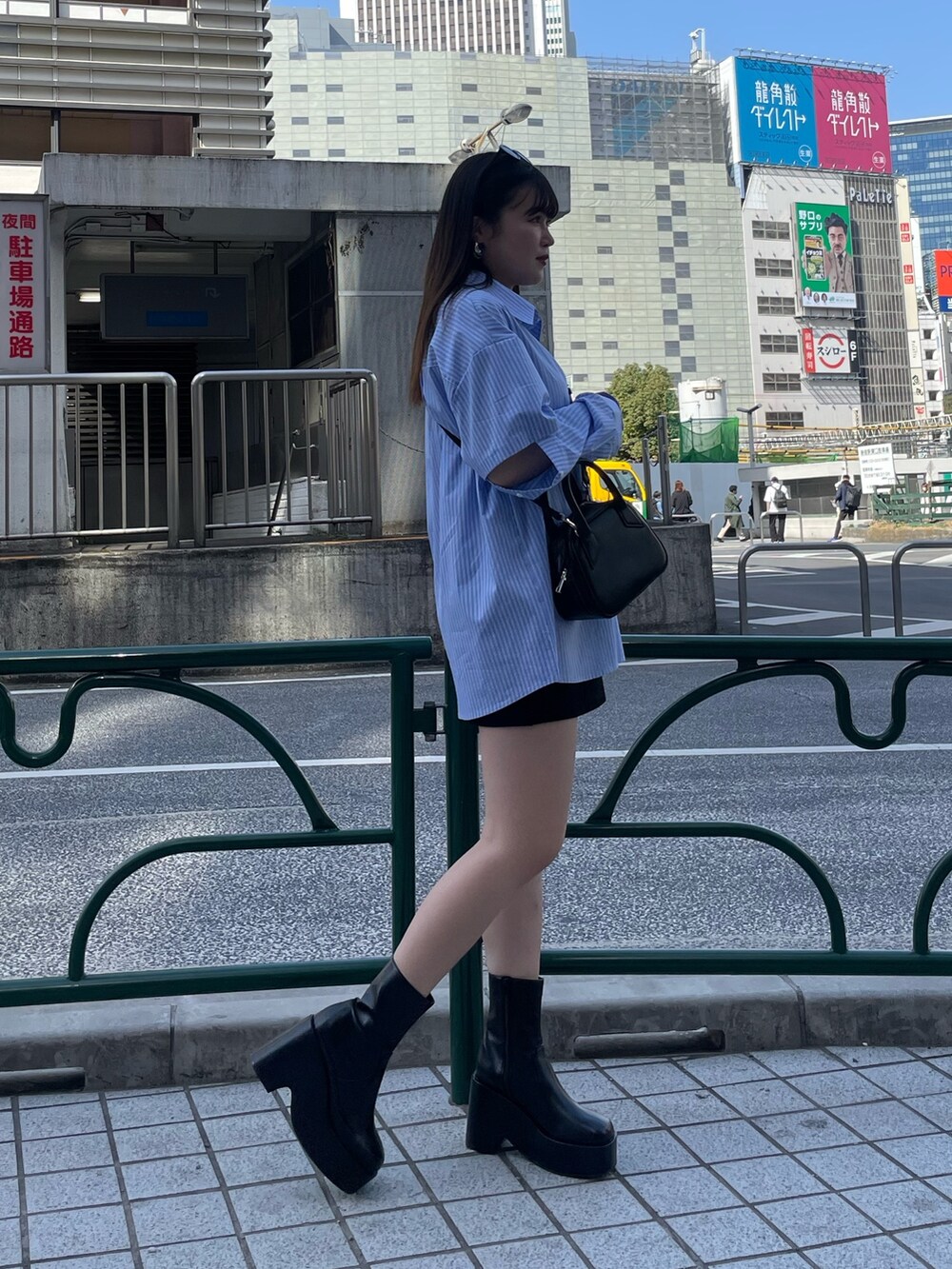 ブラック系のスカート、ブラック系のブーツ、ブラック系のハンドバッグを着用したレディースの春コーディネートの2枚目の写真